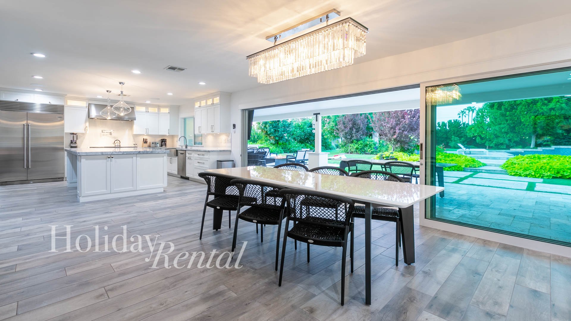 Beautiful indoor-outdoor living, featuring a dining room with large windows that slide open to the backyard, connected to the gourmet kitchen