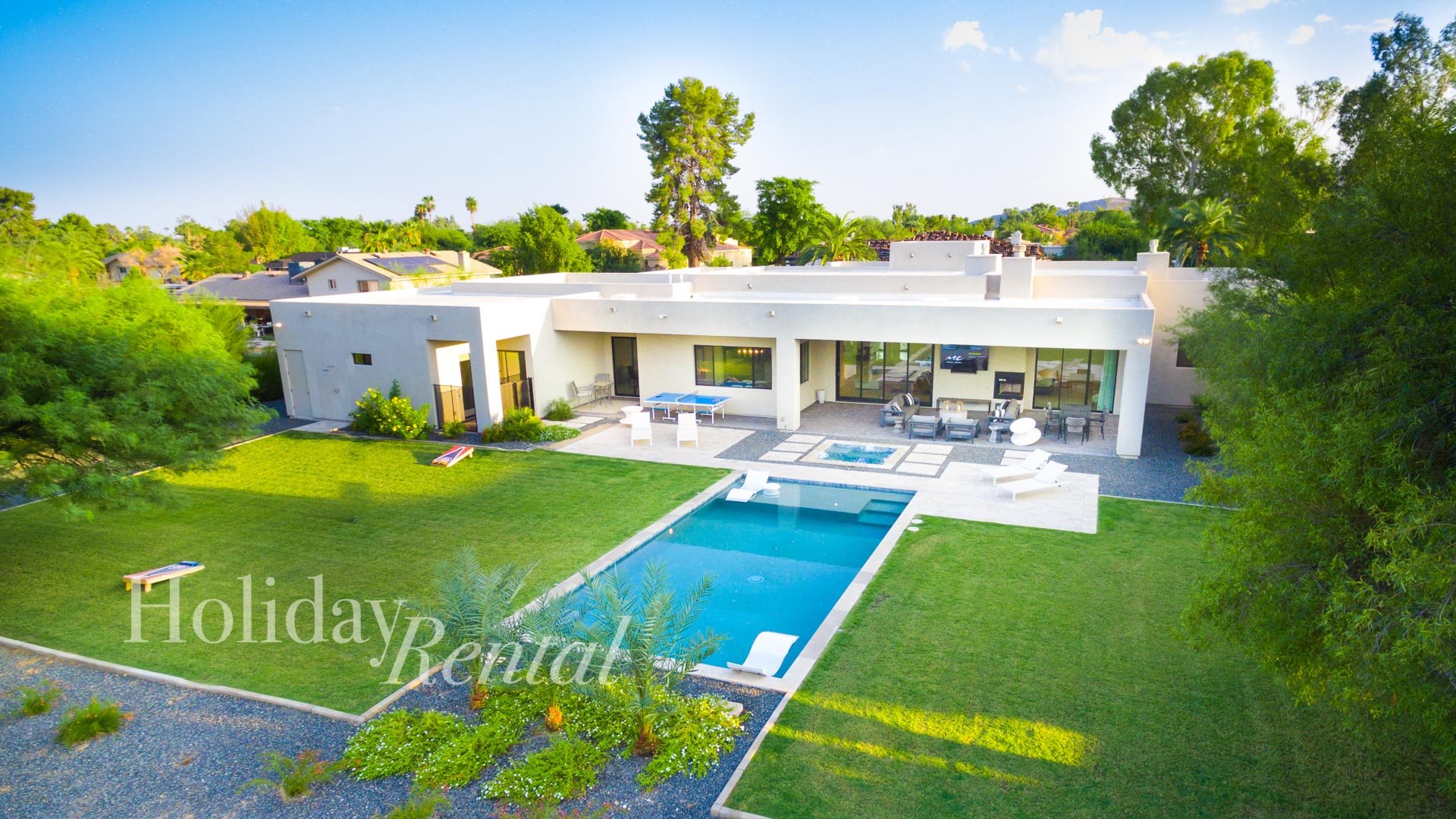 A birds-eye view of the backyard paradise, with a lush grassy area for play, a sparkling pool and spa for relaxation, a ping pong table for friendly competition, a comfortable couch seating area for l