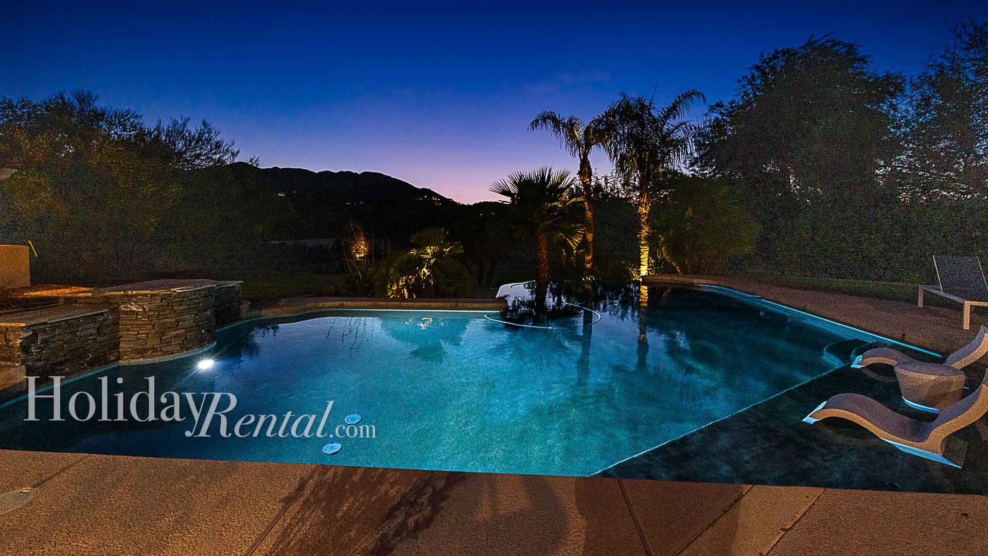 Breathtaking mountain and palm tree views from the pool at nighttime.